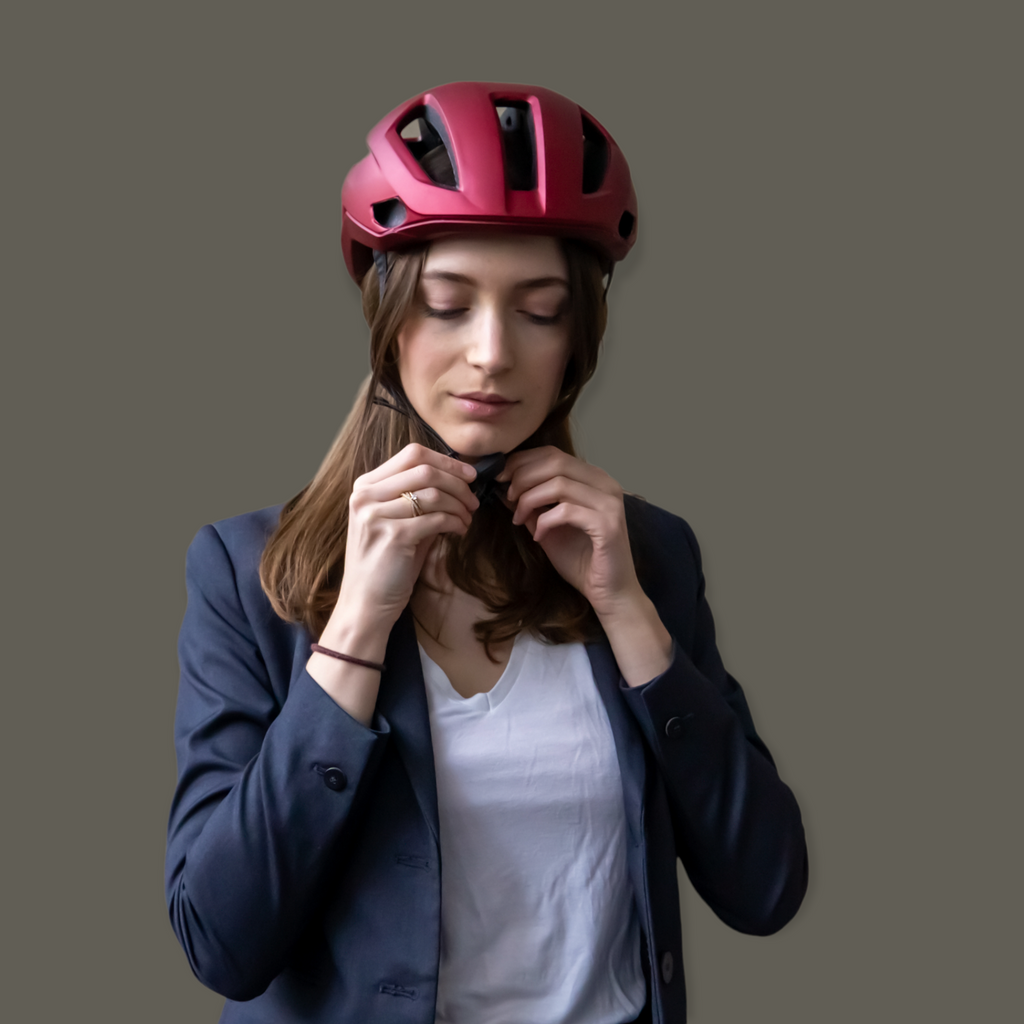 Frau zieht Burner Helmet nachhaltigen Fahrradhelm mit Fidlock Magnetverschluss an 